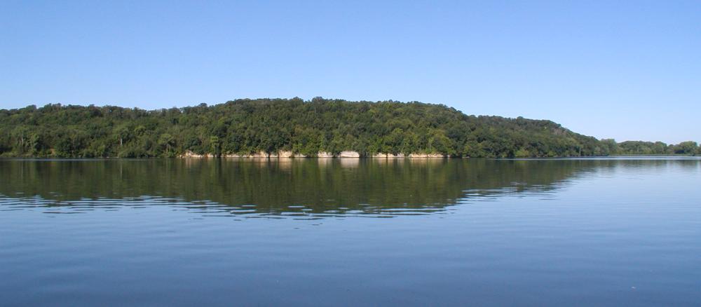 Calm lake with a tree-covered distant shoreline. 