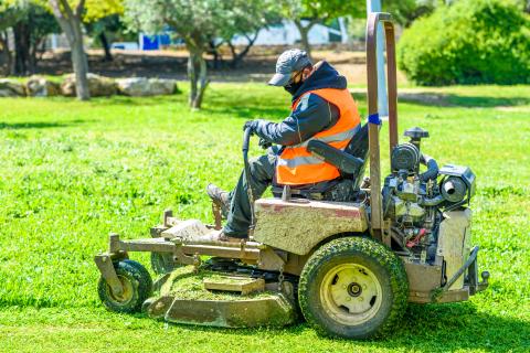 Worker mowing the grass on riding mower.