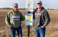 Don Tschida and son standing by signs in field that read "2022 Outstanding Conservationist of the Year" and "Minnesota Water Quality Certified Farm."