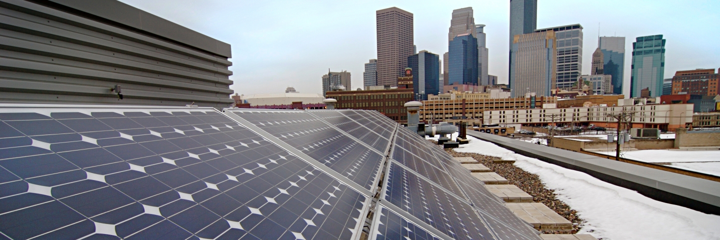 Solar panels on the rooftop of a business with downtown Minneapolis in the background.