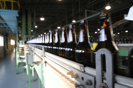 Brown bottles made from recycled glass on a conveyor line.