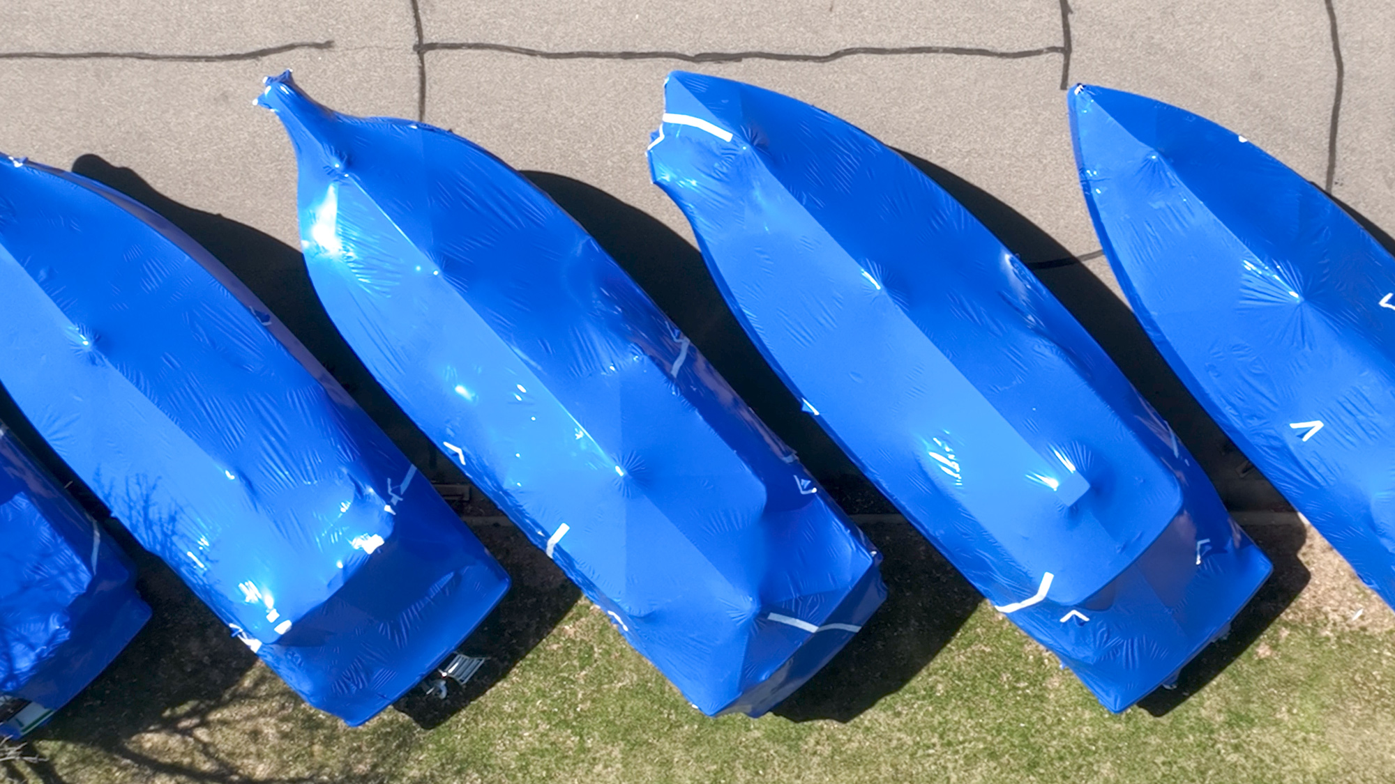 Overhead view of four boats wrapped in blue boat wrap, parked diagonally..
