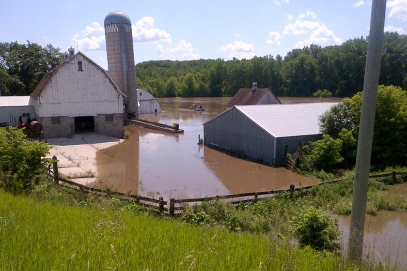 A farm yard is almost completely flooded with brown water from nearby river.
