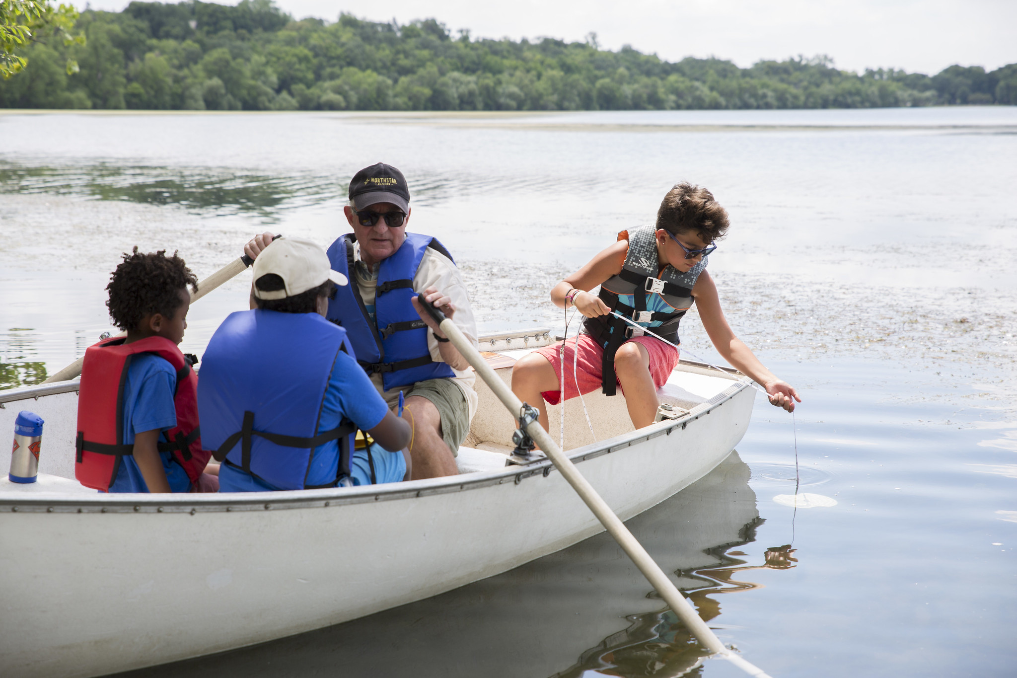 man and children on boat taking water quality readings