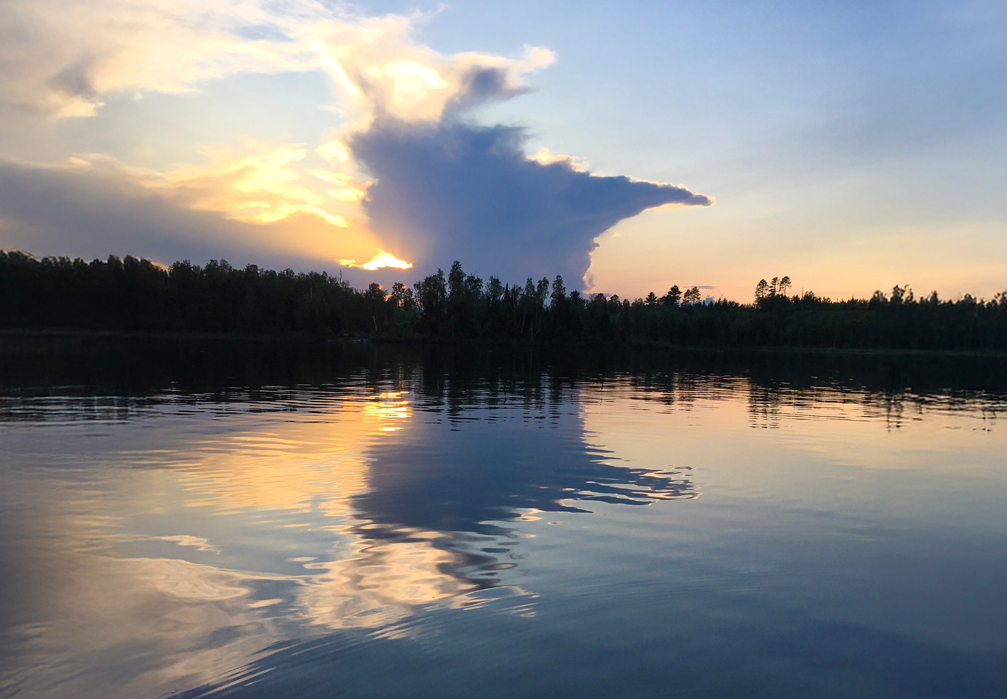 Cloud shaped like Minnesota is reflected in a calm lake.