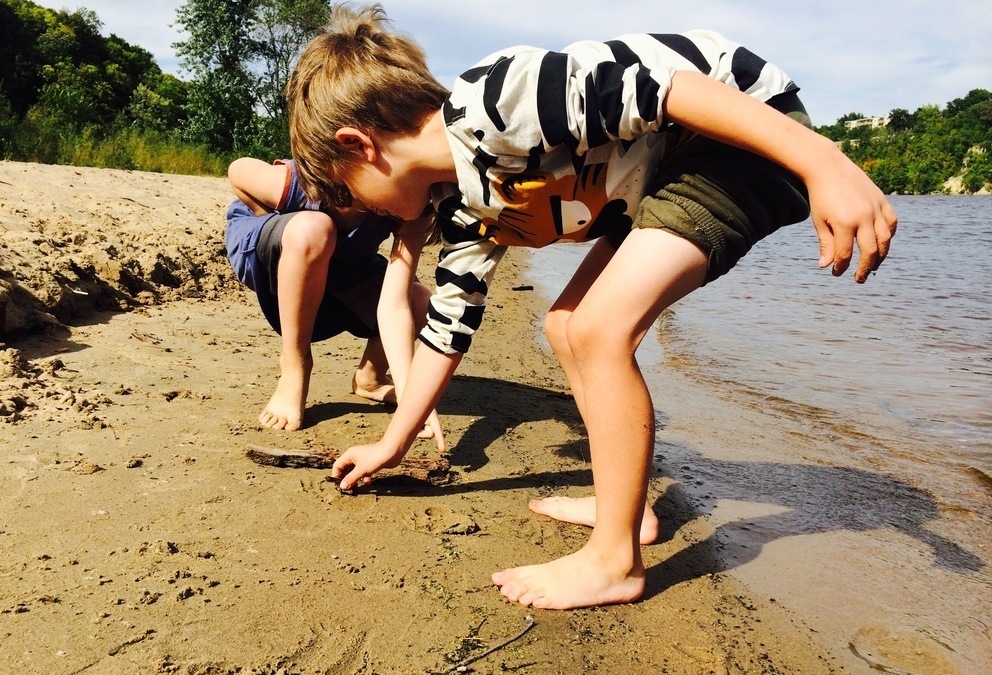 Two children playing on the beach of the Mississippi river in MN