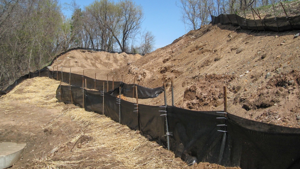 Black plastic barriers prevent soil from washing away from slopes.