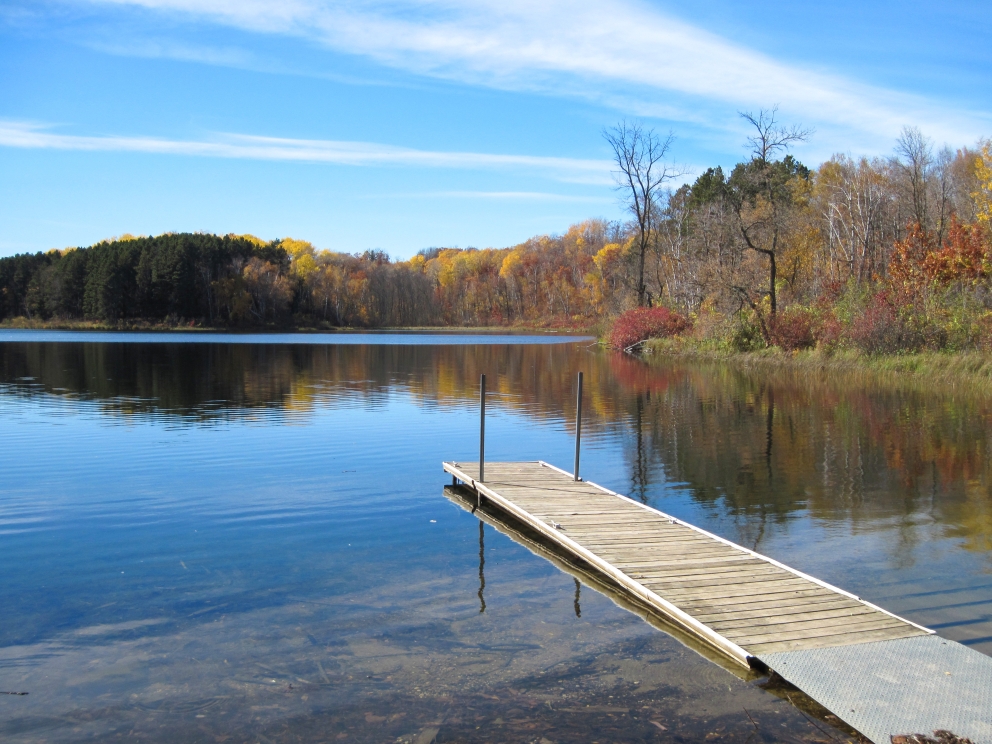 Dock extending into calm lake in the autumn.