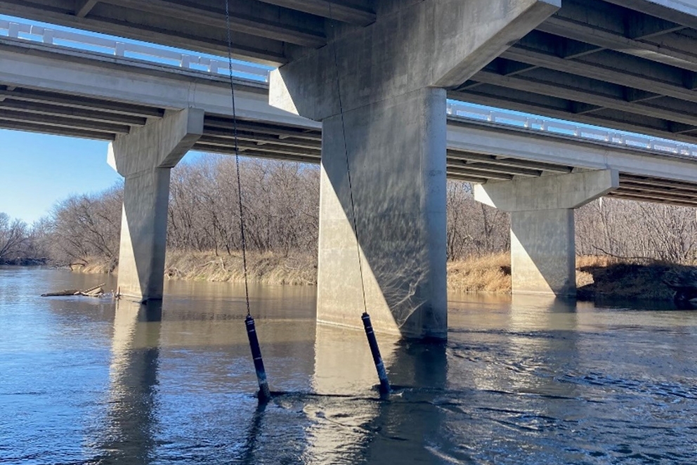 Nitrate sensors hang over a bridge into the water below