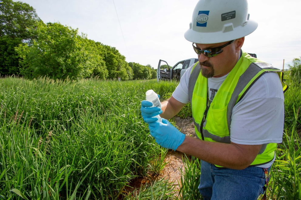 Field worker taking a water sample in a green space