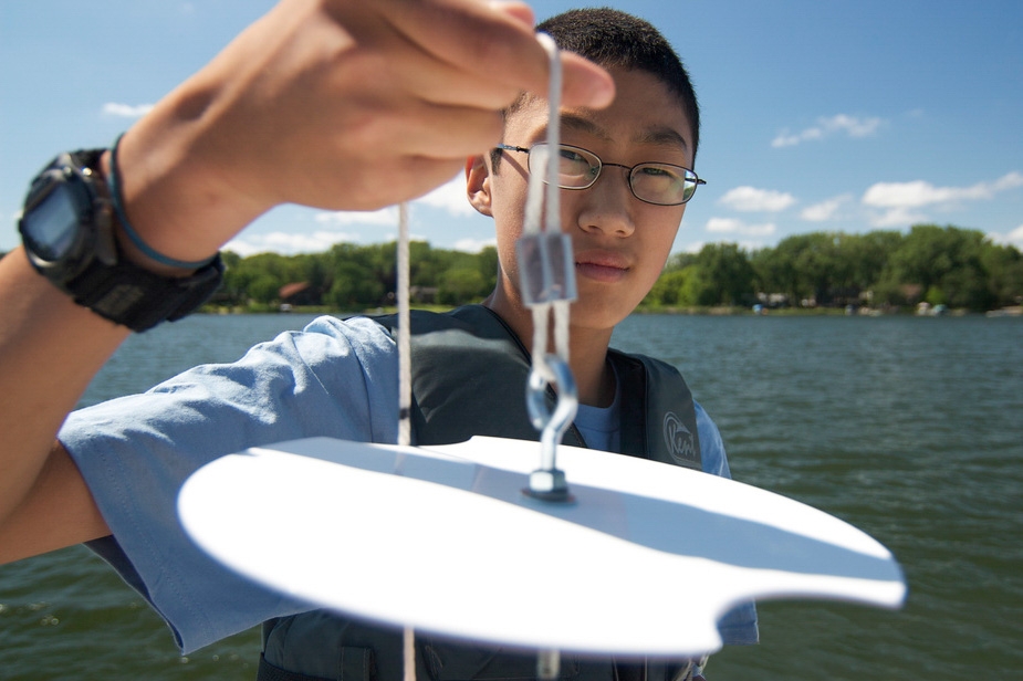 Young man holds a white secchi disk close to the camera lens