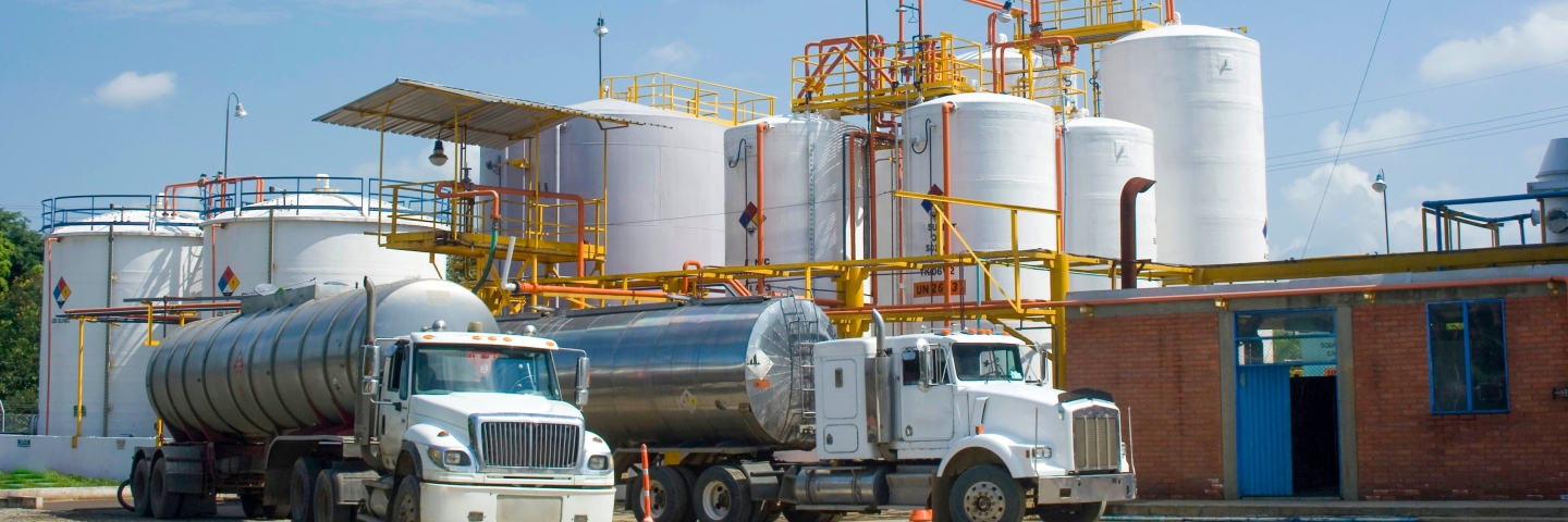 Tanker trucks parked in front of chemical storage tanks.
