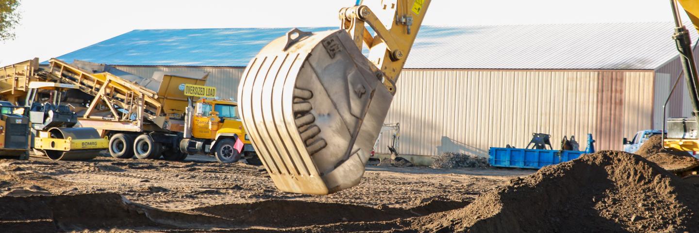 Excavator bucket over freshly dug soil.