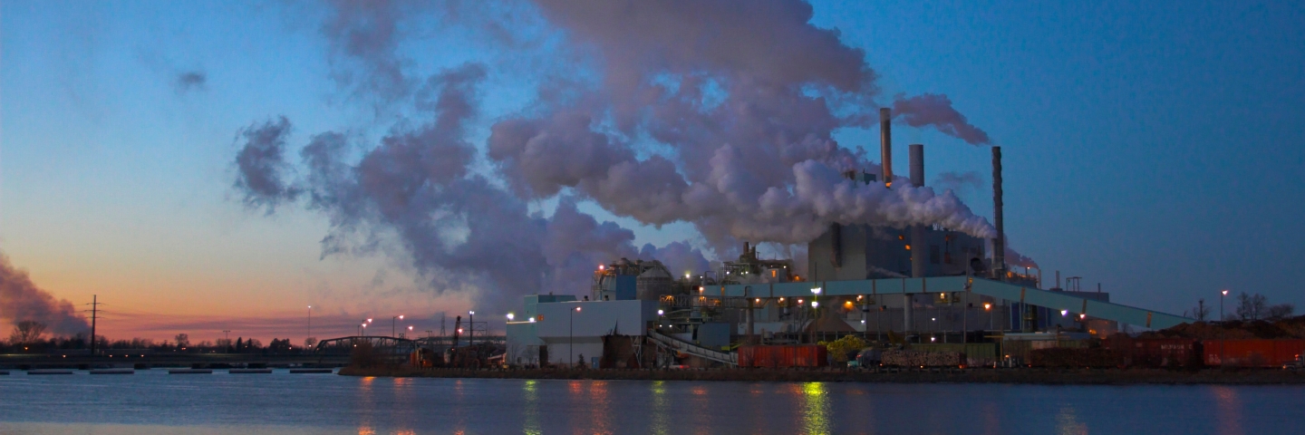 Industrial facility by river at twilight.