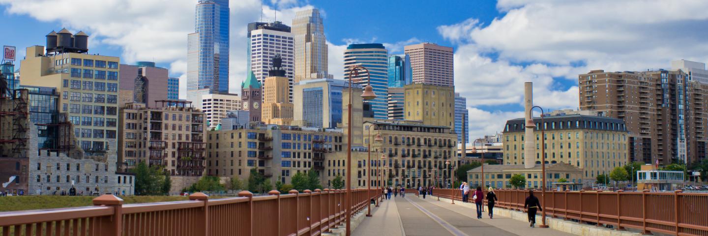 View of Minneapolis skyline, blue sky, and puffy white clouds from the Stone Arch Bridge