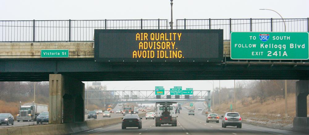 Sign over freeway saying "Air Quality Advisory, Avoid Idling"