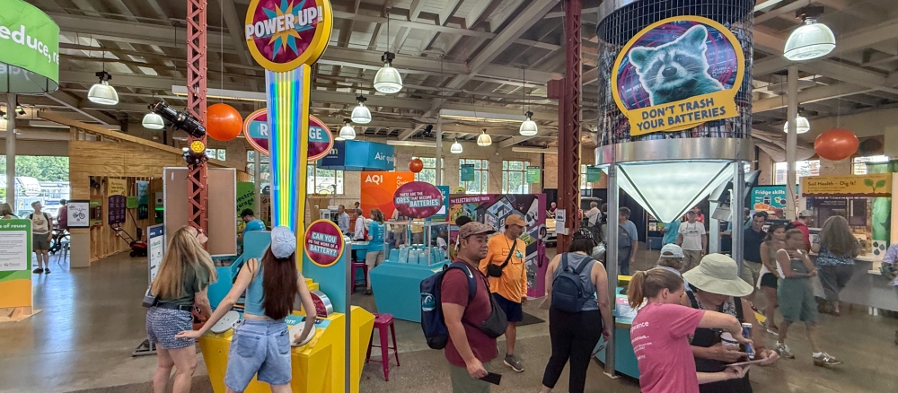 People interacting with educational exhibits about batteries.