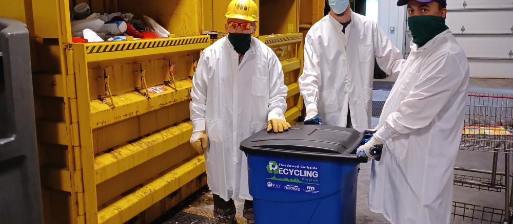 City workers standing next to recycling baler