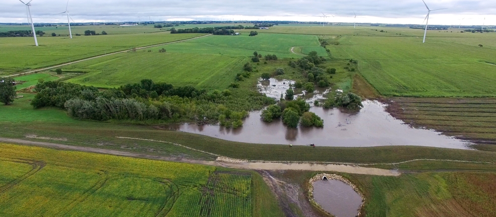 Aerial view of flooding in farm fields with a stormwater berm in the foreground.