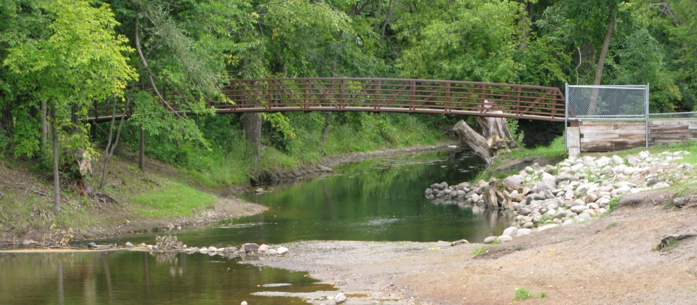 A footbridge crosses a small river.
