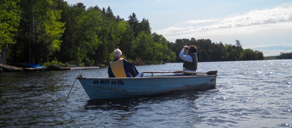 Two men in a blue fishing boat on a lake.