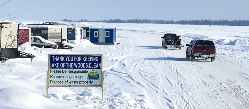 Icehouses and pickups on frozen Lake of the Woods. A sign says "Thank you for keeping Lake of the Woods clean."