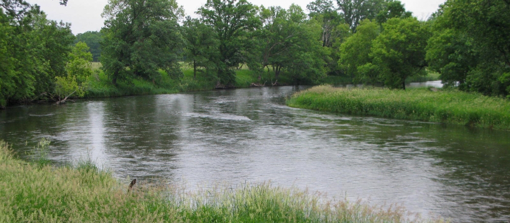 Curving stream running through grassy banks.