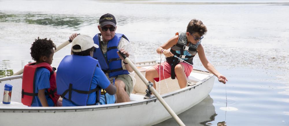 man and children on boat taking water quality readings