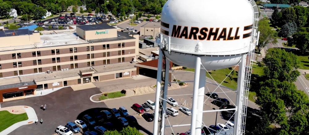 Aerial view of a white water tower with the name "Marshall" painted on it. 