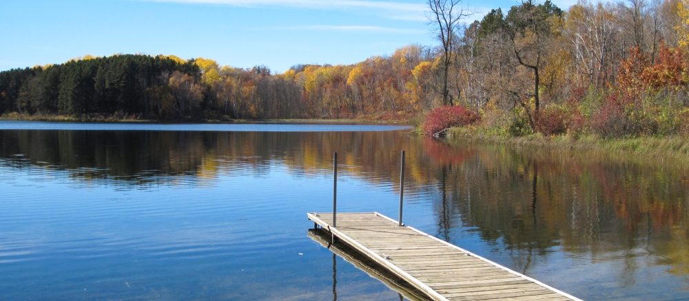 Dock extending into calm lake in the autumn.