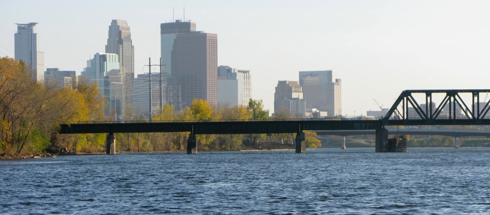 Railroad bridge crossing the Mississippi River with the Minneapolis skyline in background.