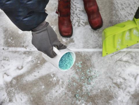 Pouring salt from a coffe mug on icy sidewalk