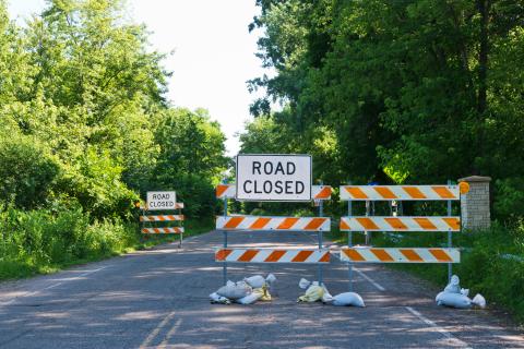 Barricades blocking road with signs that say "road closed".