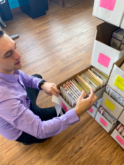 A man selecting from medications filed in a box to fill a prescription.