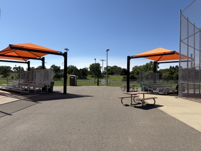 Two orange canopies provide shade over bleachers at Aquila Park in St. Louis Park, Minnesota. 