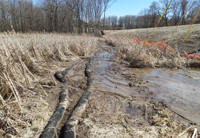 Mud from road construction flowing over sediment filter socks into a wetland.