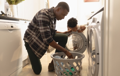 Father and son putting clothes in washing machine.
