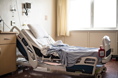 Empty hospital bed with rumpled covers.