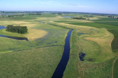 Aerial view of a straight narrow waterway running through fields.