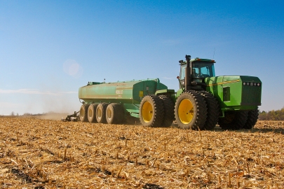 John Deere tractor in a disked farm field pulling a manure injector. 