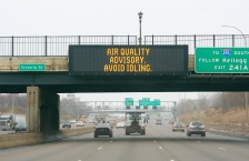 Sign over freeway saying "Air Quality Advisory, Avoid Idling"