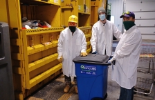 City workers standing next to recycling baler