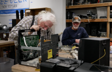 A Free Geek volunteer and community member sit together and examine a broken stereo