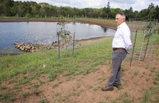 A man stands outside next to a pond in a stormwater garden.