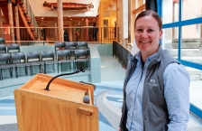 A woman standing in front of a lectern smiling at the camera.