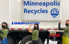 Three women flexing biceps of right arm stand in front of recycling truck with sign that reads Minneapolis Reycyles.