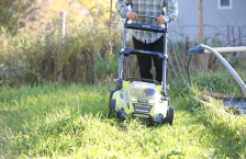 Person cutting grass with an electric lawnmower