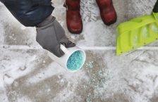 Pouring salt from a coffe mug on icy sidewalk