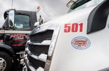Close up of the grill of a white heavy-duty truck with two stickers that says "certified clean idle."