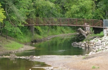 A footbridge crosses a small river.